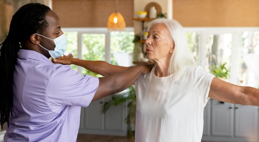 Care worker helping an older woman exercise at home